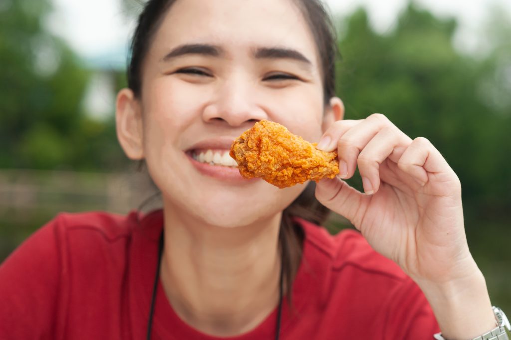 woman smiling while eating fried chicken